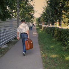 a man with a suitcase leaves on the sidewalk