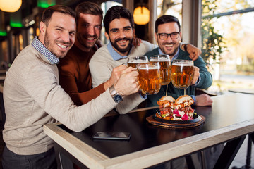 A group of friends toast to a beer at pub
