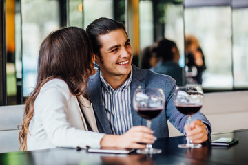 Romantic young couple enjoying dinner at cafe, relationship and romantic time, happy celebrating and making cheers with glasses of red wine.
