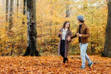 Fototapeta premium Family and hot autumn drink concept. Couple in love holding cups of tea or coffee and walking.