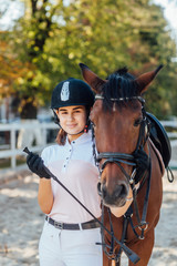 Obraz premium Young woman jockey in special uniform and helmet with her riding horse.