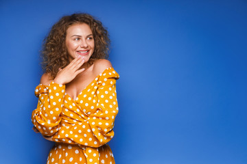 Image of happy young lady standing isolated over blue background. Looking camera pointing. Nice woman. Copy space.