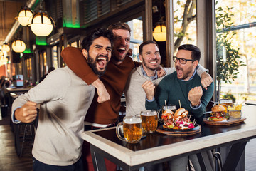 Excited group cheering for sport team in pub