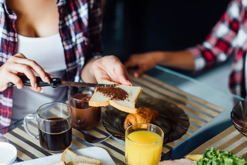 Woman hands spreading chocolate butter on the bread in the morning breakfast on table.