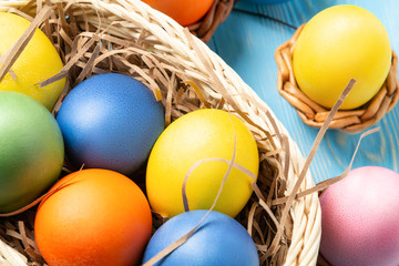 Fototapeta na wymiar Easter composition - several colored eggs in a basket on a blue wooden table, top view