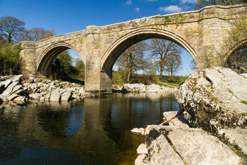 Fototapeta na wymiar Beautiful old stone arch bridge over river.
