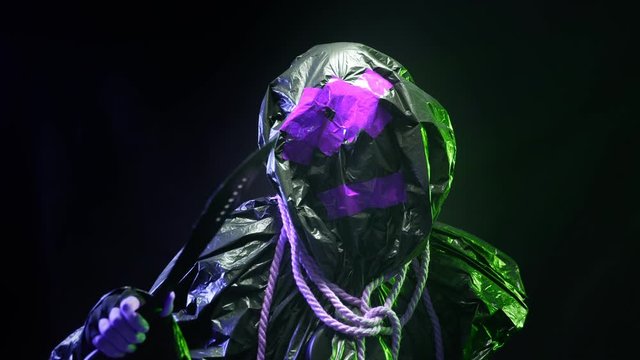 black plastic monster with a machete in his hand on a black background, flashing psychedelic light