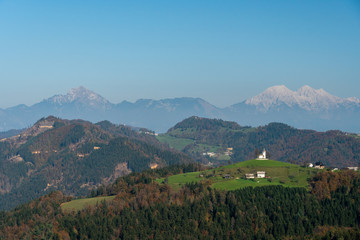 Slovenian rural mountain village with Kamnik Alps in the background, landscape view.