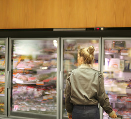 Fototapeta na wymiar Woman choosing frozen food from a supermarket freezer 