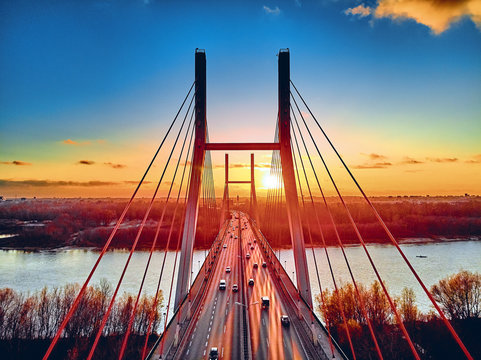 Beautiful panoramic aerial drone view to cable-stayed Siekierkowski Bridge over the Vistula river and Warsaw City skyscrapers, Poland in gold red autumn colors in November evening at sunset