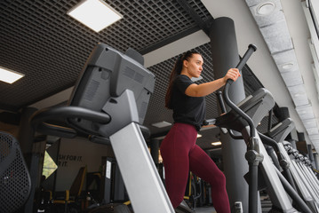 Fototapeta na wymiar attractive young woman runs on a treadmill, is engaged in fitness sport club