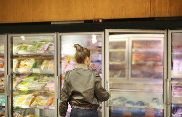 Woman choosing frozen food from a supermarket freezer	