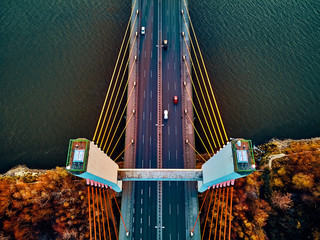 Beautiful panoramic aerial drone view to cable-stayed Siekierkowski Bridge over the Vistula river and Warsaw City skyscrapers, Poland in gold red autumn colors in November evening at sunset - top down