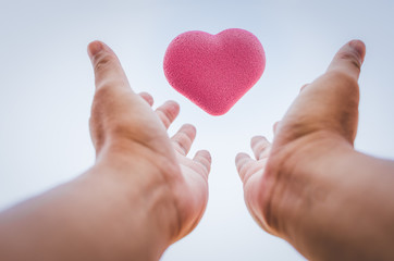 pink heart shaped bubble floating above human plam