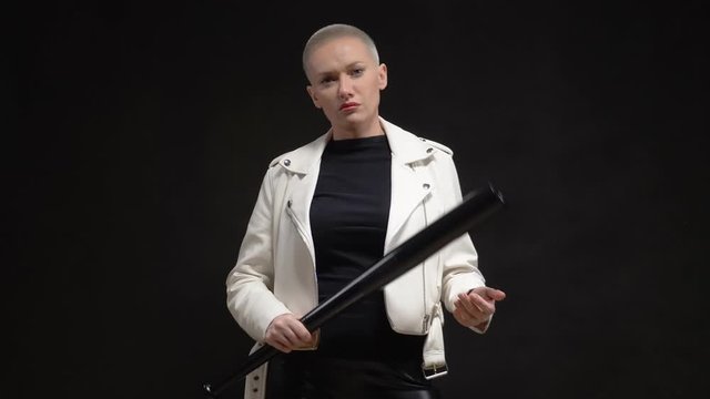 beautiful blonde short haired woman in a white leather jacket with a baseball bat on a black background