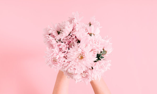 Beautiful Flowers Composition. Women's Hand Hold Bouquet Of Pink Light Flowers On Pastel Pink Background. Valentines Day, Mother's Day. Flat Lay, Top View, Copy Space