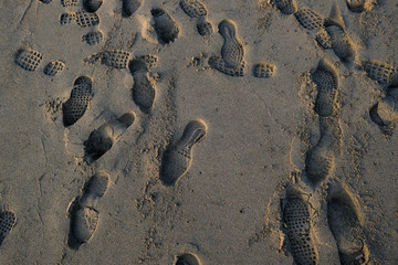Human shoes steps footprints on wild sandy sea beach,texture wallpaper