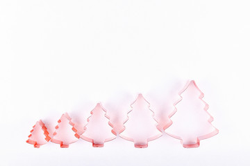 Flatlay with row of holiday tree copper cookie cutters on white sparkling background. Holiday, Christmas and New Year concept. Cozy homey details Flat lay, top view background. Horizontal
