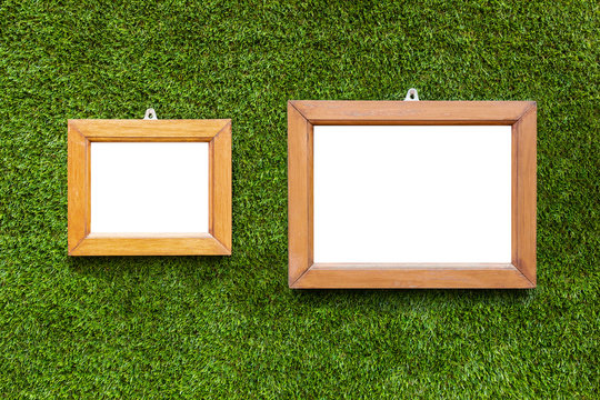 Blank picture frame hanging on artificial grass wall background