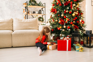 Obraz na płótnie Canvas Beautiful little girl playing with a Christmas gift box