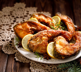 Fried carp fish slices on a ceramic plate on the holiday table, close up. Traditional christmas eve dish. Polish Christmas