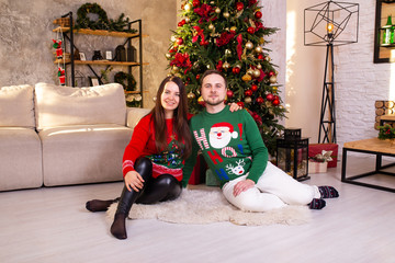 Wife and husband near Christmas tree at home.