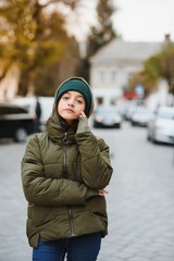 stylish beautiful teen girl on the street in a hat and jacket