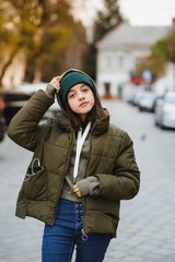 stylish beautiful teen girl on the street in a hat and jacket