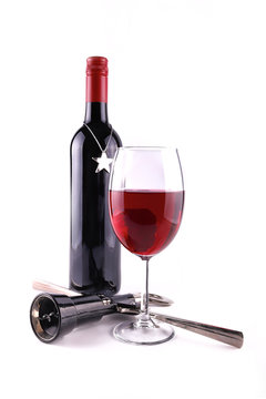 Glass of the red wine, cork screw and a bottle with Christmas ornament isolated on white, shallow focus