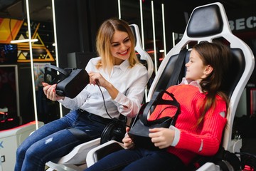 Entertainment. Cheerful fair-haired young mother and daughter wearing VR headset and entertaining.