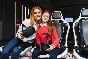 Fototapeta na wymiar Entertainment. Cheerful fair-haired young mother and daughter wearing VR headset and entertaining.