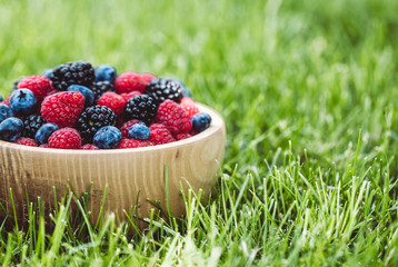 raspberries and blackberries in wood bowl on table, vintage