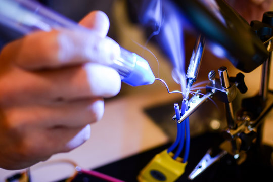 Smoke appears while soldering ESC and rotor wires with helper hands. Technology and electrical engineering concept. Autonomous vehicles like drones need a lot of soldering in building process