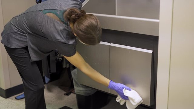 A janitor custodian woman cleaning doctors office medical area to prevent transmission of disease and germs 