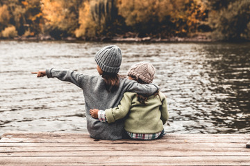 Happy children, little girls, sit and play on a wooden bridge. Portrait. Landscape orientation.