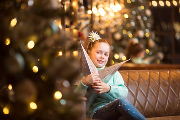 portrait of a beautiful teenage girl sitting on a sofa near a festive Christmas tree