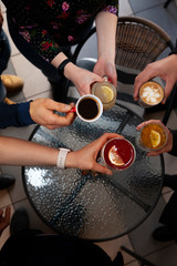 The company of friends holds different types of tea and coffee