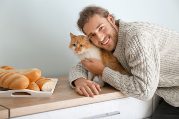 Man with cute cat in kitchen