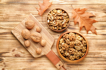 Tasty walnuts with autumn leaves on wooden table