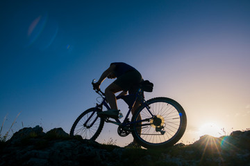 Plakat Silhouette of a mountain biker riding his mountain sportbike on top of a cliff ( hill).