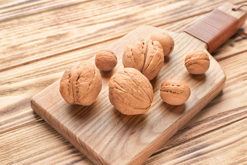 Board with tasty walnuts on wooden table