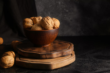 Bowl with tasty walnuts on wooden boards