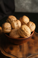 Bowl with tasty walnuts on wooden board, closeup