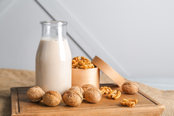 Bottle of milk with tasty walnuts on table