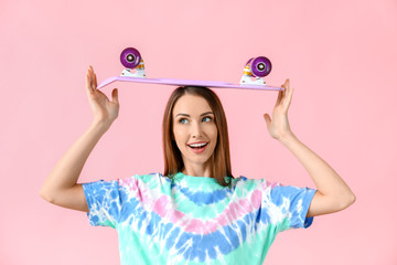 Beautiful young woman with skateboard on color background