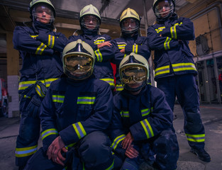 Portrait of group firefighters in front of firetruck inside the fire station