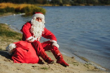 Santa Claus in swimming suit walking along the beach
