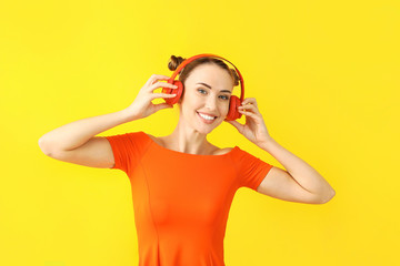 Beautiful young woman listening to music on color background