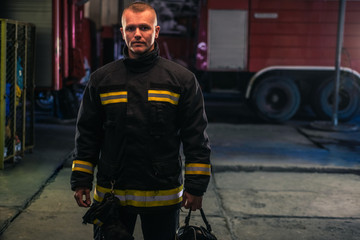 Fototapeta premium Portrait of young fireman standing inside the fire station.