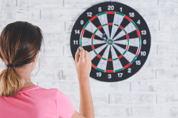 Young woman playing darts indoors
